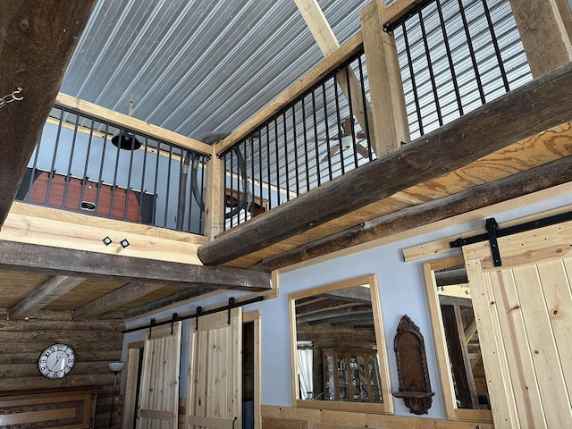 interior details with a barn door, beam ceiling, and log walls