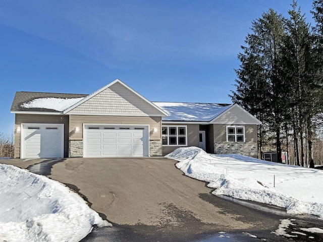 view of front of home featuring stone siding, an attached garage, and driveway