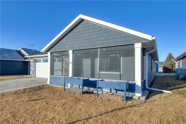 view of front of home featuring a garage, concrete driveway, a front lawn, and central AC unit