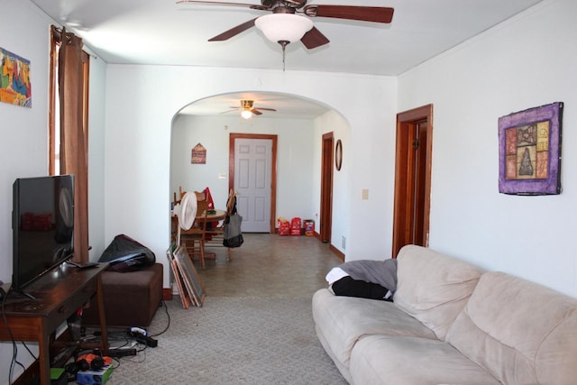 living room featuring carpet, crown molding, arched walkways, and a ceiling fan