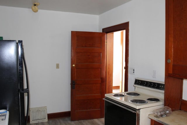 kitchen with wood finished floors, visible vents, light countertops, freestanding refrigerator, and white range with electric cooktop