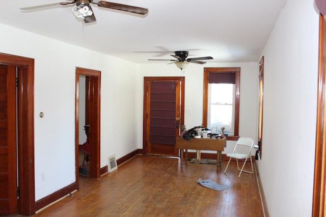 foyer featuring baseboards, wood-type flooring, visible vents, and a ceiling fan