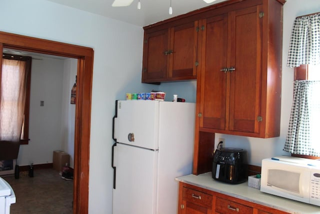 kitchen with ceiling fan, light countertops, white appliances, and brown cabinetry