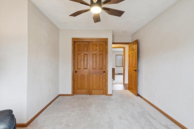 unfurnished bedroom with carpet floors, a closet, a ceiling fan, and baseboards