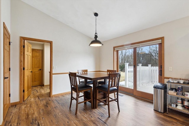 dining area featuring lofted ceiling, baseboards, and wood finished floors