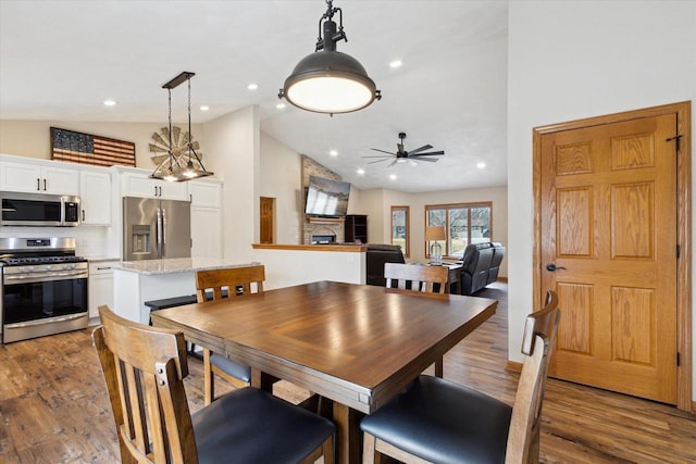 dining area with ceiling fan, wood finished floors, a fireplace, high vaulted ceiling, and recessed lighting