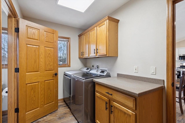 clothes washing area featuring cabinet space, independent washer and dryer, and wood finished floors