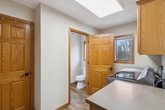 bathroom with toilet, wood finished floors, visible vents, baseboards, and washer and clothes dryer