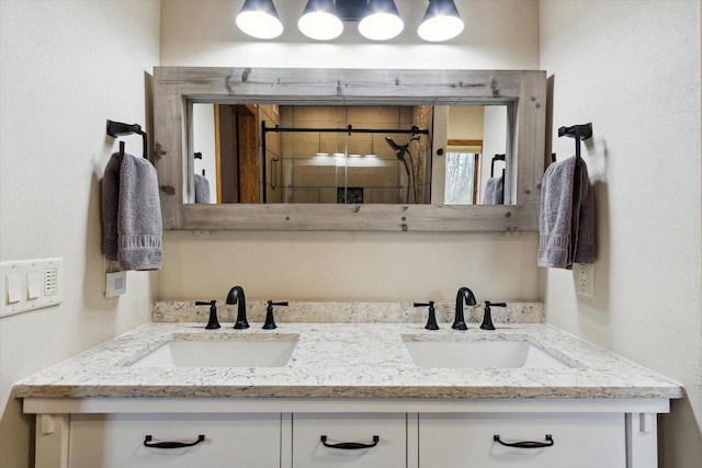 bathroom featuring double vanity, a stall shower, and a sink