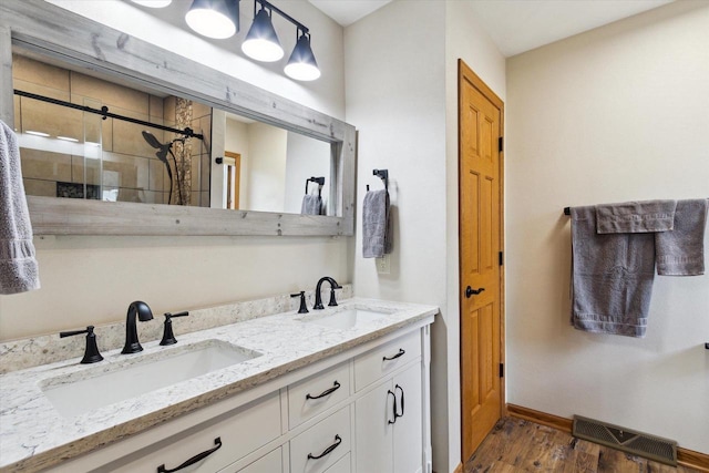 bathroom with wood finished floors, a stall shower, a sink, and visible vents