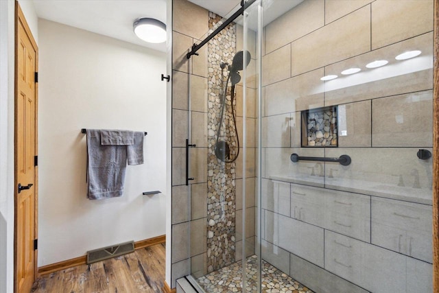 bathroom with baseboards, visible vents, wood finished floors, a shower stall, and a sink