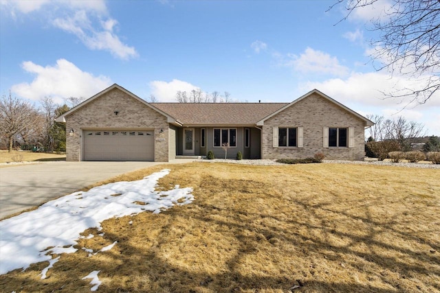 ranch-style house with driveway, brick siding, an attached garage, and a front yard