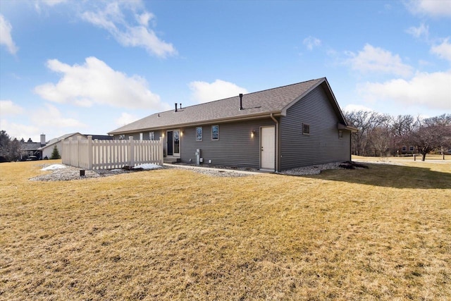 back of property featuring a lawn and fence