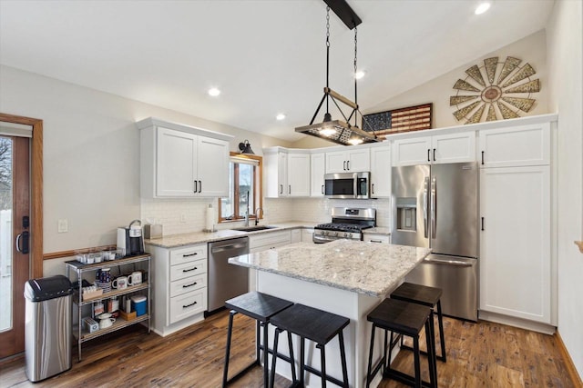 kitchen with tasteful backsplash, appliances with stainless steel finishes, dark wood-style flooring, vaulted ceiling, and a sink