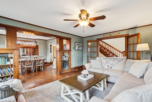 living room with ceiling fan, ornamental molding, wood finished floors, and baseboards