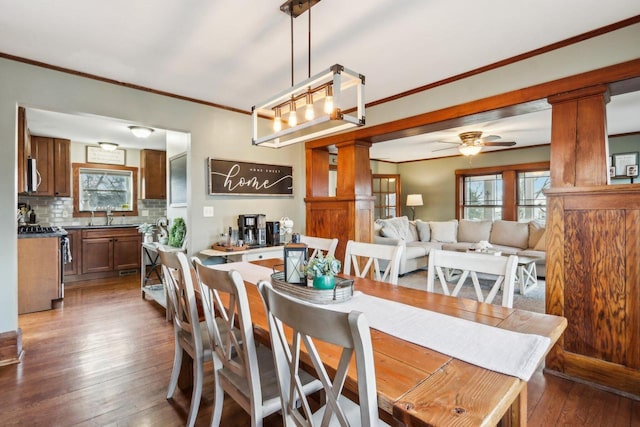 dining space featuring ornamental molding, dark wood-type flooring, ceiling fan, and ornate columns