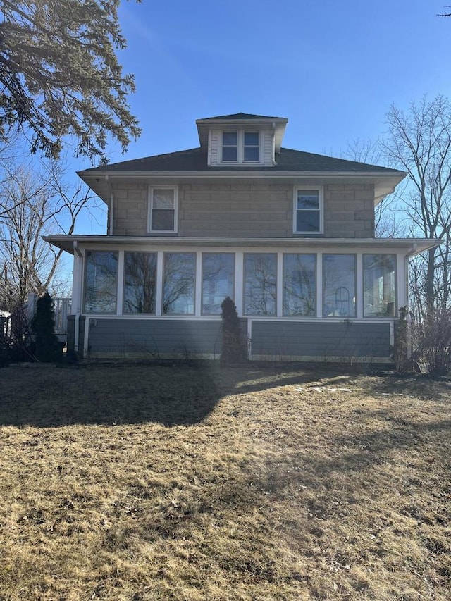 rear view of property with a lawn and a sunroom