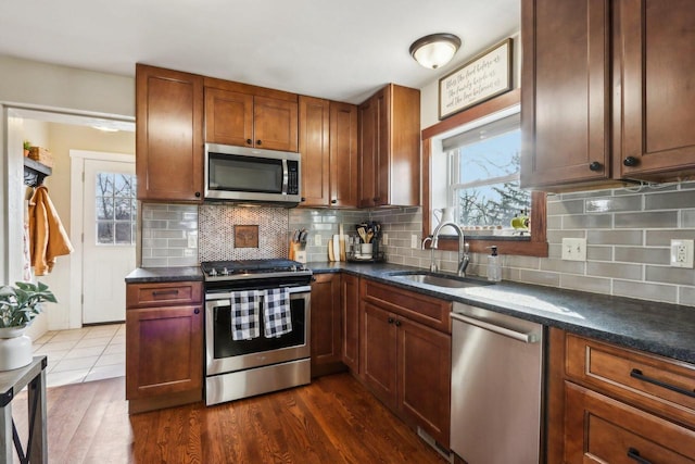 kitchen with dark wood-style flooring, appliances with stainless steel finishes, backsplash, and a sink