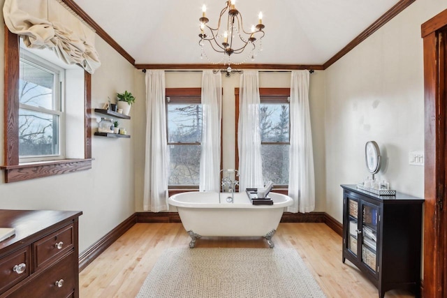 bathroom with ornamental molding, lofted ceiling, a healthy amount of sunlight, and wood finished floors