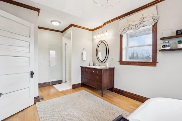 bathroom with wood finished floors, vanity, baseboards, walk in shower, and crown molding