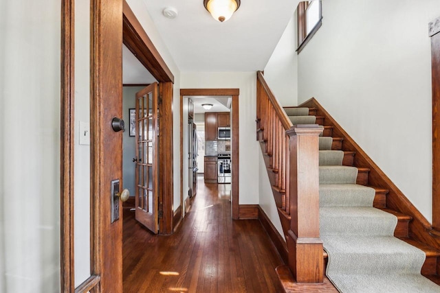 foyer entrance with dark wood-style floors, stairs, and baseboards