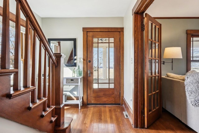 entrance foyer with wood-type flooring, visible vents, stairway, and baseboards