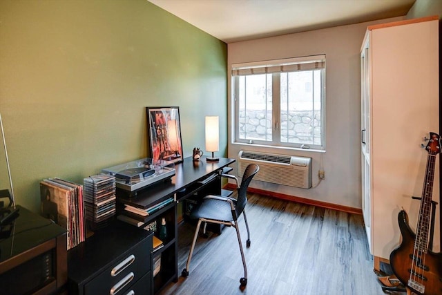 office area featuring baseboards, wood finished floors, and a wall mounted air conditioner