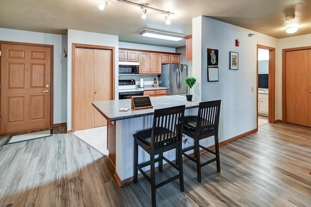 kitchen featuring electric range, baseboards, a breakfast bar, freestanding refrigerator, and light wood-style floors