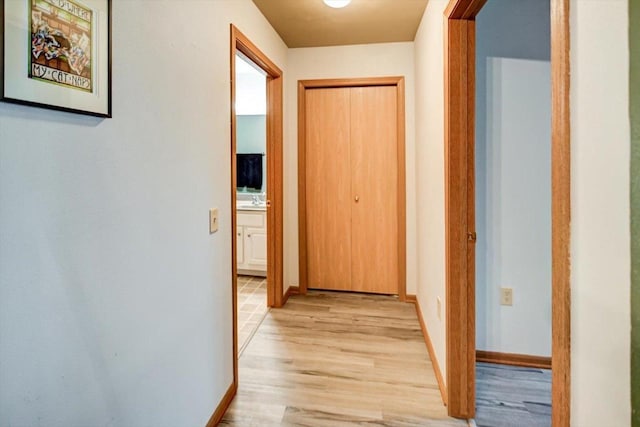 hallway with light wood-type flooring and baseboards