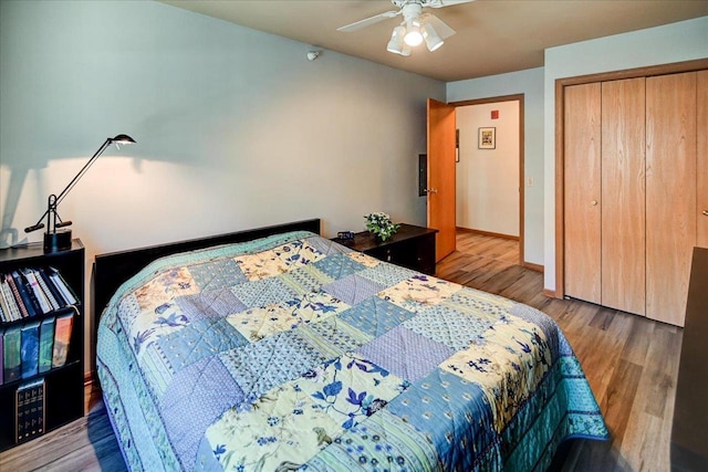 bedroom with a closet, wood finished floors, a ceiling fan, and baseboards