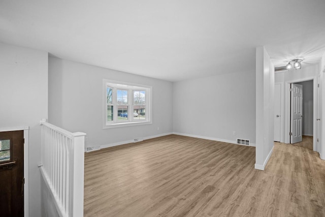 unfurnished living room featuring light wood-style flooring, visible vents, and baseboards