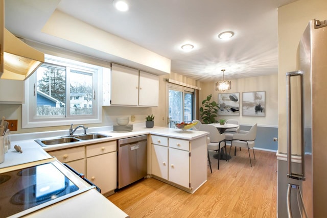 kitchen with dishwasher, light countertops, light wood finished floors, and a sink