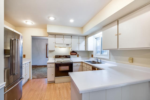 kitchen featuring range with electric stovetop, high end fridge, light countertops, a sink, and under cabinet range hood