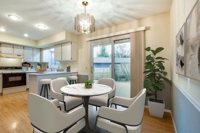 dining space with light wood-style floors, recessed lighting, a notable chandelier, and baseboards