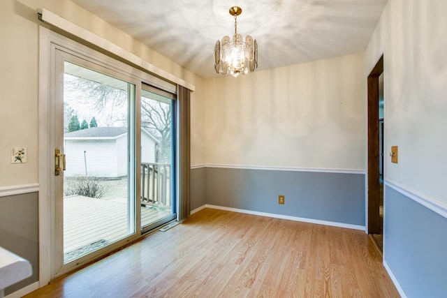 unfurnished room featuring a notable chandelier, baseboards, and wood finished floors