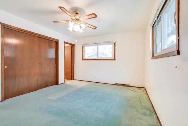 unfurnished bedroom featuring carpet floors, ceiling fan, visible vents, and baseboards