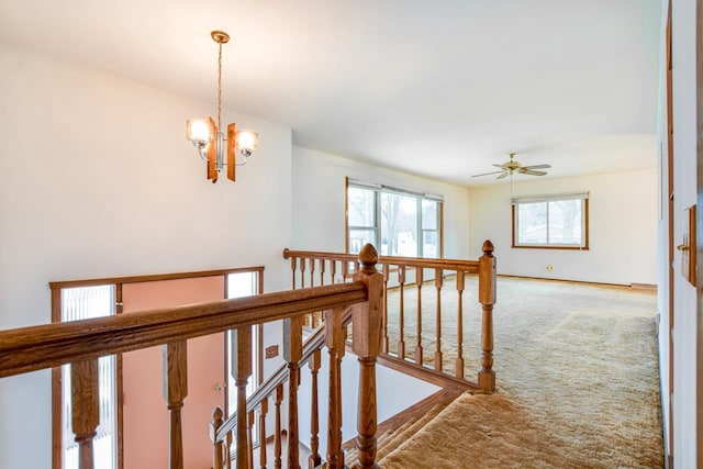 hallway featuring carpet, a notable chandelier, and an upstairs landing