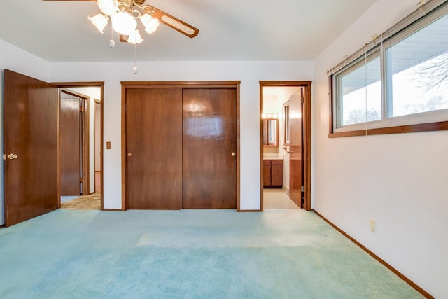 unfurnished bedroom featuring baseboards, a closet, ensuite bathroom, and light colored carpet