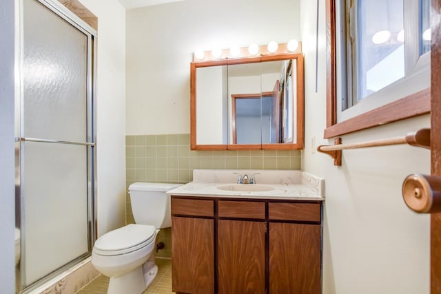 full bath with a stall shower, tile walls, toilet, and vanity