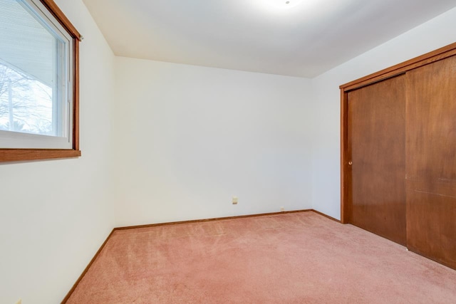 unfurnished bedroom with carpet floors, a closet, and baseboards