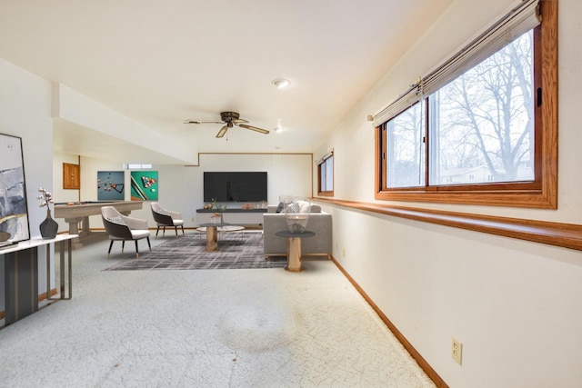 living room featuring carpet, baseboards, and a ceiling fan