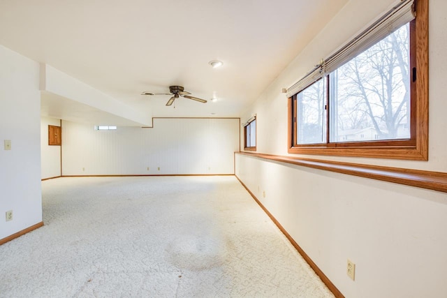 carpeted spare room featuring ceiling fan and baseboards