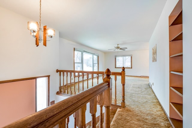 hallway with baseboards, carpet flooring, a notable chandelier, and an upstairs landing