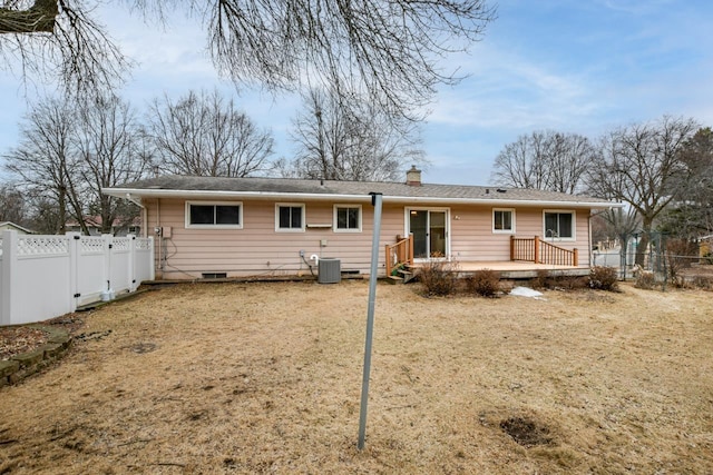 back of house with a fenced backyard, a chimney, and central AC