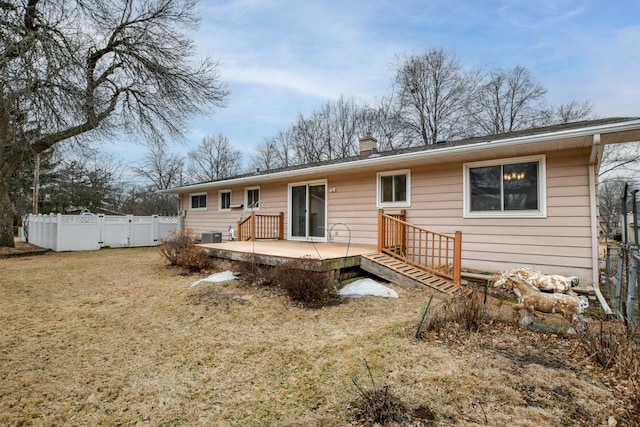 rear view of property featuring a yard, a chimney, central AC, fence, and a wooden deck