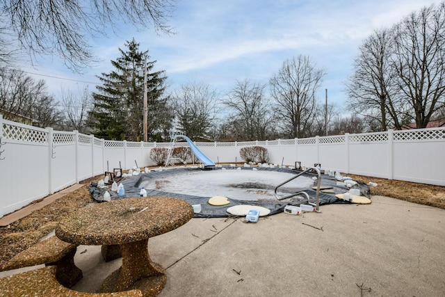 view of pool with a patio area, a fenced backyard, and a water slide