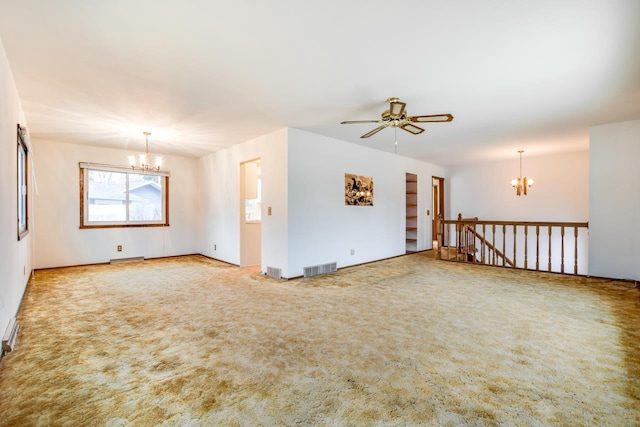 spare room featuring ceiling fan with notable chandelier, carpet, and visible vents