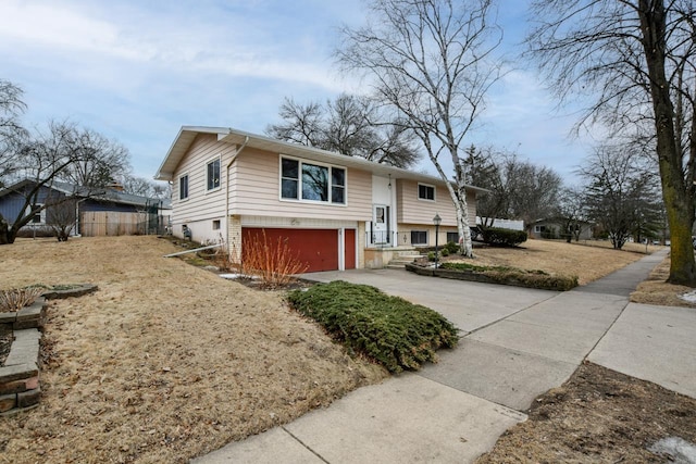 split foyer home with an attached garage, fence, and concrete driveway