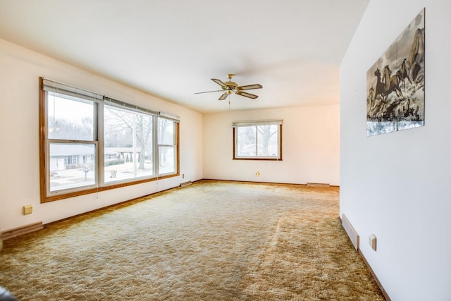 carpeted empty room featuring a ceiling fan and baseboards