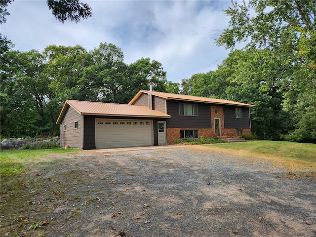 view of front facade with a garage, driveway, metal roof, and brick siding